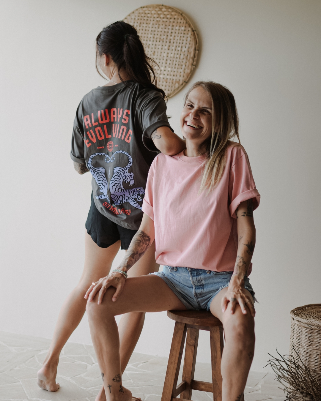 Two women wearing Fair Artisan Always Evolving t-shirts